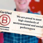 A photo of the author holding B Corp Certification plaque in mark-making*s reception