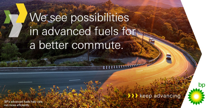 Vehicles drive down a curving, sunlit road, bathed in autumn sunshine, surrounded by trees. the caption reads 'We see possibilities in advanced fuels for a better commute.  Adjacent to the green BP logo, the tagline reads 'keep advancing"
